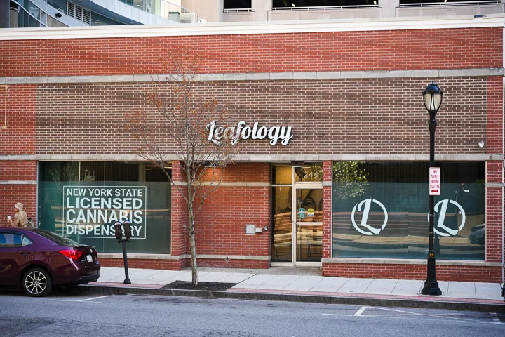 Leafology storefront: brick facade with cyan 'Leafology' sign and NY State Licensed Cannabis Dispensary decal, downtown White Plains