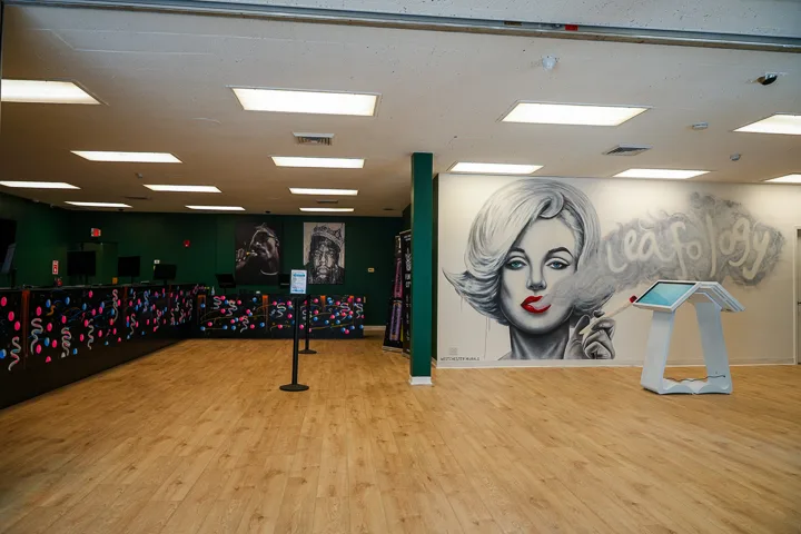 Leafology sales floor with Marilyn mural, self-order kiosk, Biggie and Tupac portraits, graffiti counter